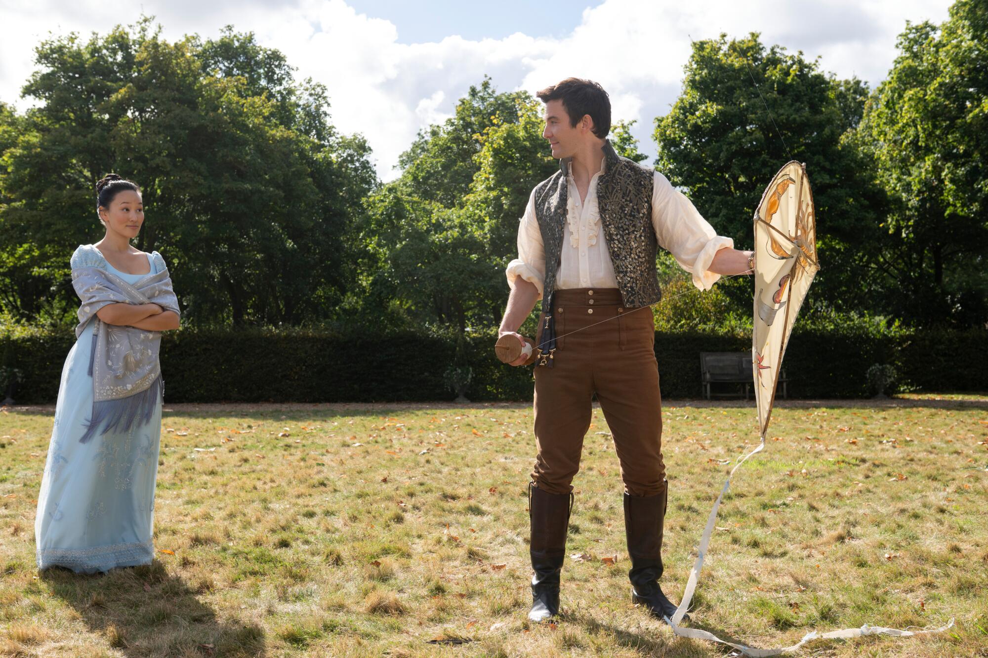 A man holds a kite while a woman looks on