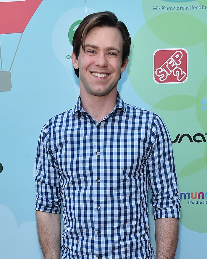 Young man in blue checkered shirt smiling at an event, related to Little Rascals star and Catholic extremist news.