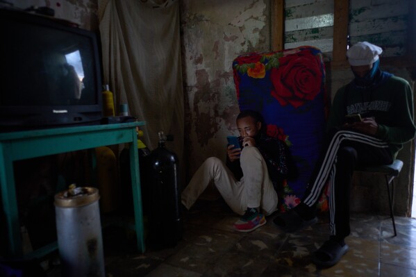 Youths use their cell phones during a scheduled blackout to ration energy, at their home in Santa Cruz del Norte, home to one of Cuba’s largest thermoelectric plants, Tuesday, Feb. 3, 2026. (AP Photo/Ramon Espinosa)