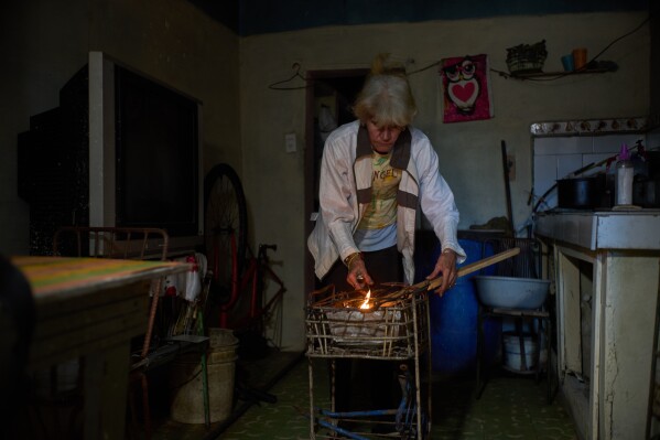 Minorkys Hoyos Ruiz lights coals to cook dinner during a scheduled blackout to ration energy in Santa Cruz del Norte, home to one of Cuba’s largest thermoelectric plants, late afternoon Tuesday, Feb. 3, 2026. (AP Photo/Ramon Espinosa)