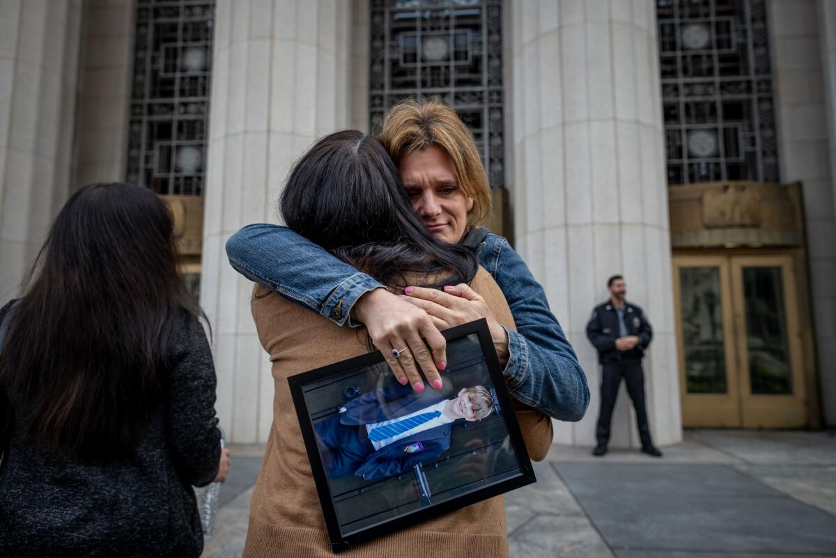 People holding photos of their children embrace outside the court Wednesday.