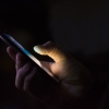 a hand holding a smart phone in the dark