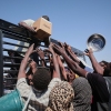 Sudanese families displaced from El-Fasher reach out as aid workers distribute food supplies at the newly established El-Afadh camp in Al Dabbah, in Sudan's Northern State, Sunday, Nov. 16, 2025.