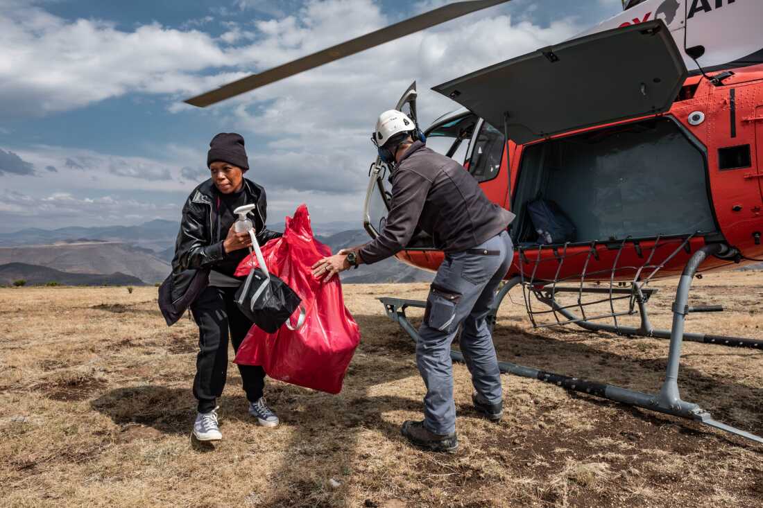 Dental therapist Senate Makhoali of the Lesotho Flying Doctor Services unloads her equipment from a Mercy Air helicopter after being dropped near the isolated village of Mophooko in the highlands of Lesotho. Senate had never before been in a plane before joining the Lesotho Flying Doctor Services in May 2024.