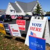 A Vote Here sign is posted amongst political signs as people arrive to vote at the Rutherford County Annex Building, an early voting site, Oct. 17, 2024, in Rutherfordton, N.C.