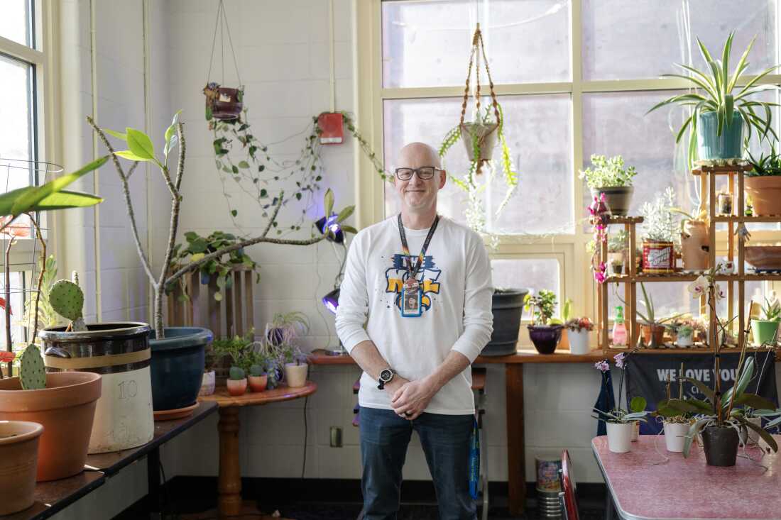 Anton Caldwell, the school librarian, stands in a room filled with potted plants.
