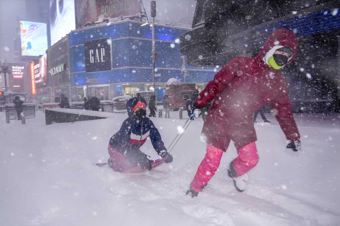 Hannah and Astrid Grimskog play in Times Square during a snow storm, Monday, Feb. 23, 2026, in New York.