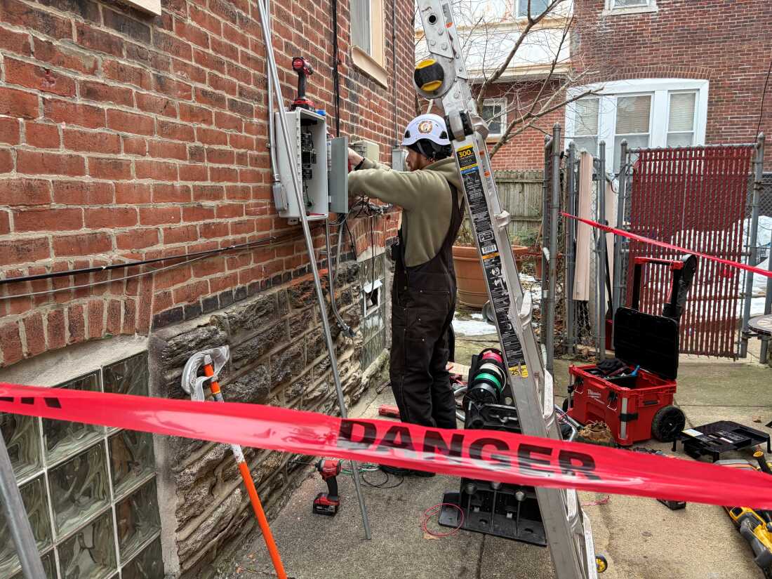 Solar States employee Doug McIntyre installs wiring for a new rooftop solar project in North Philadelphia.