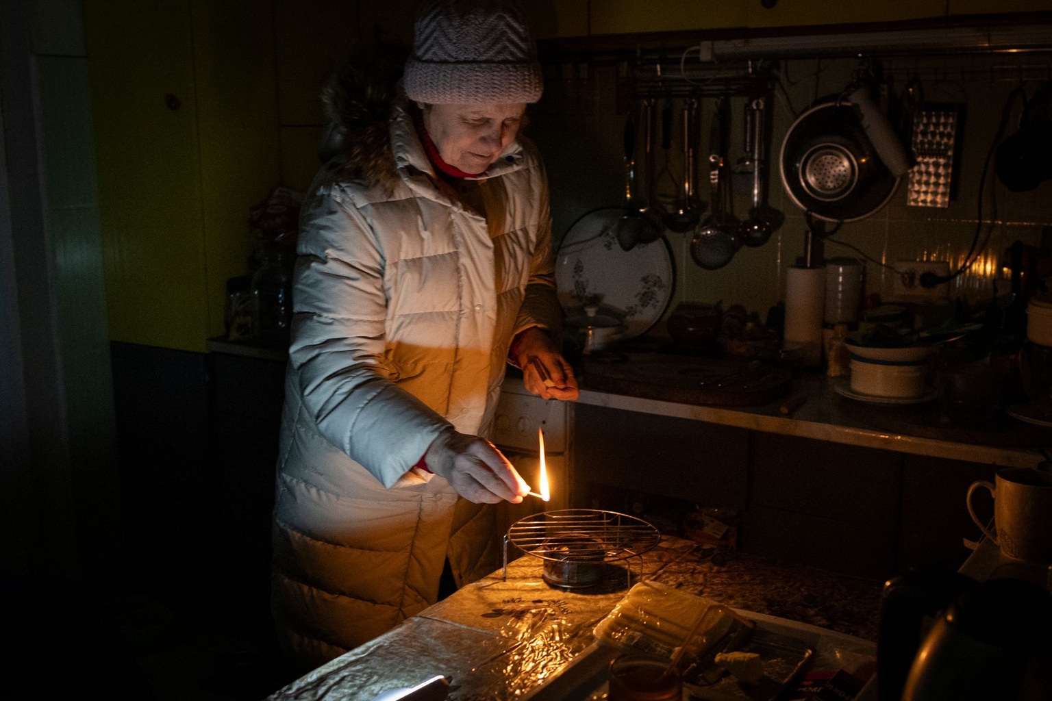 Raisa Donbekirova, 65, lights an alcohol trench candle, the only source of heat in her apartment left without water, electricity and heating after Russian shelling of critical infrastructure in Kyiv, Ukraine, on Jan. 10, 2026.
