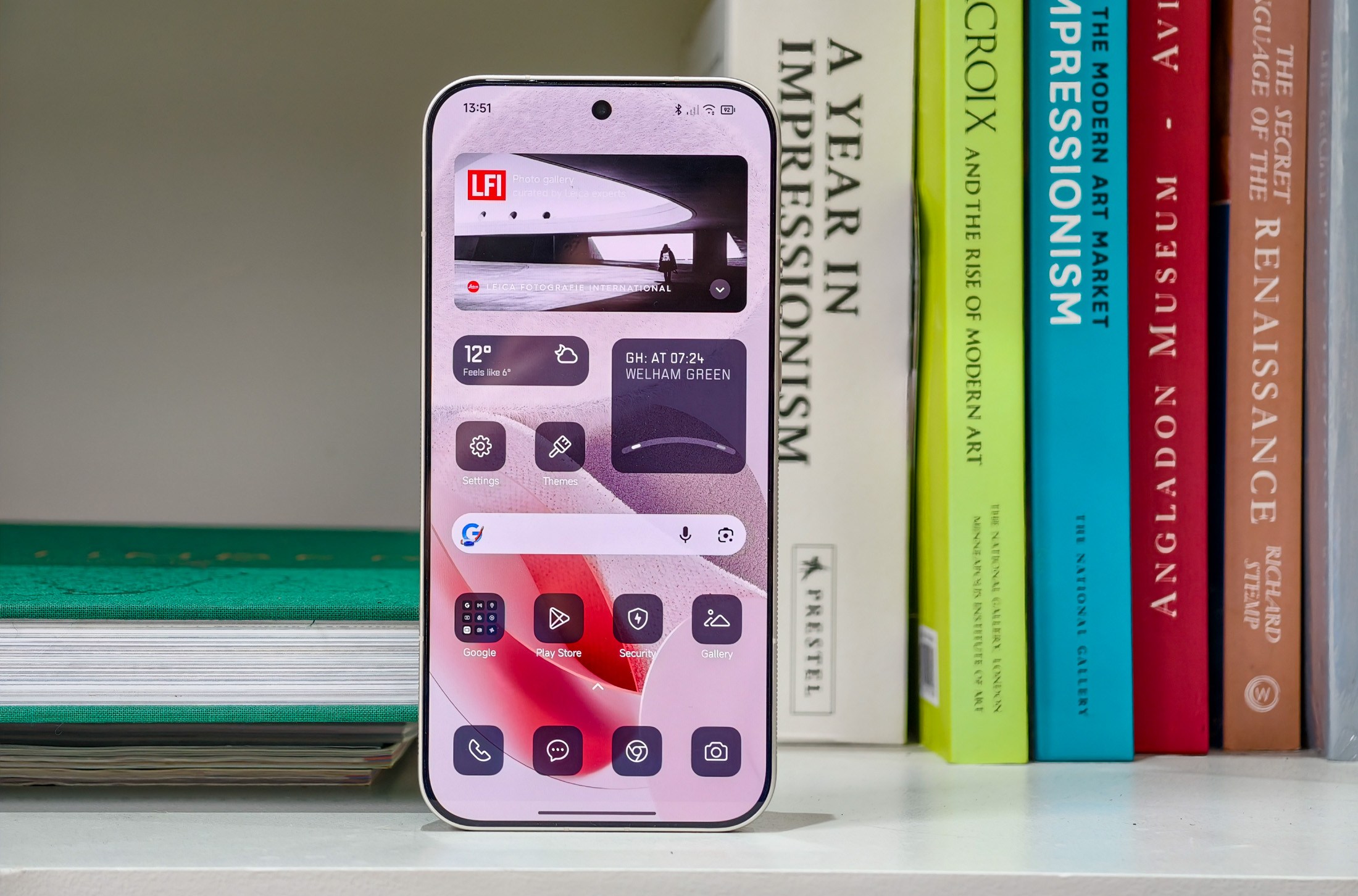 Photo of the Xiaomi Leica Leitzphone on a bookshelf, showing the home screen with monochrome widgets
