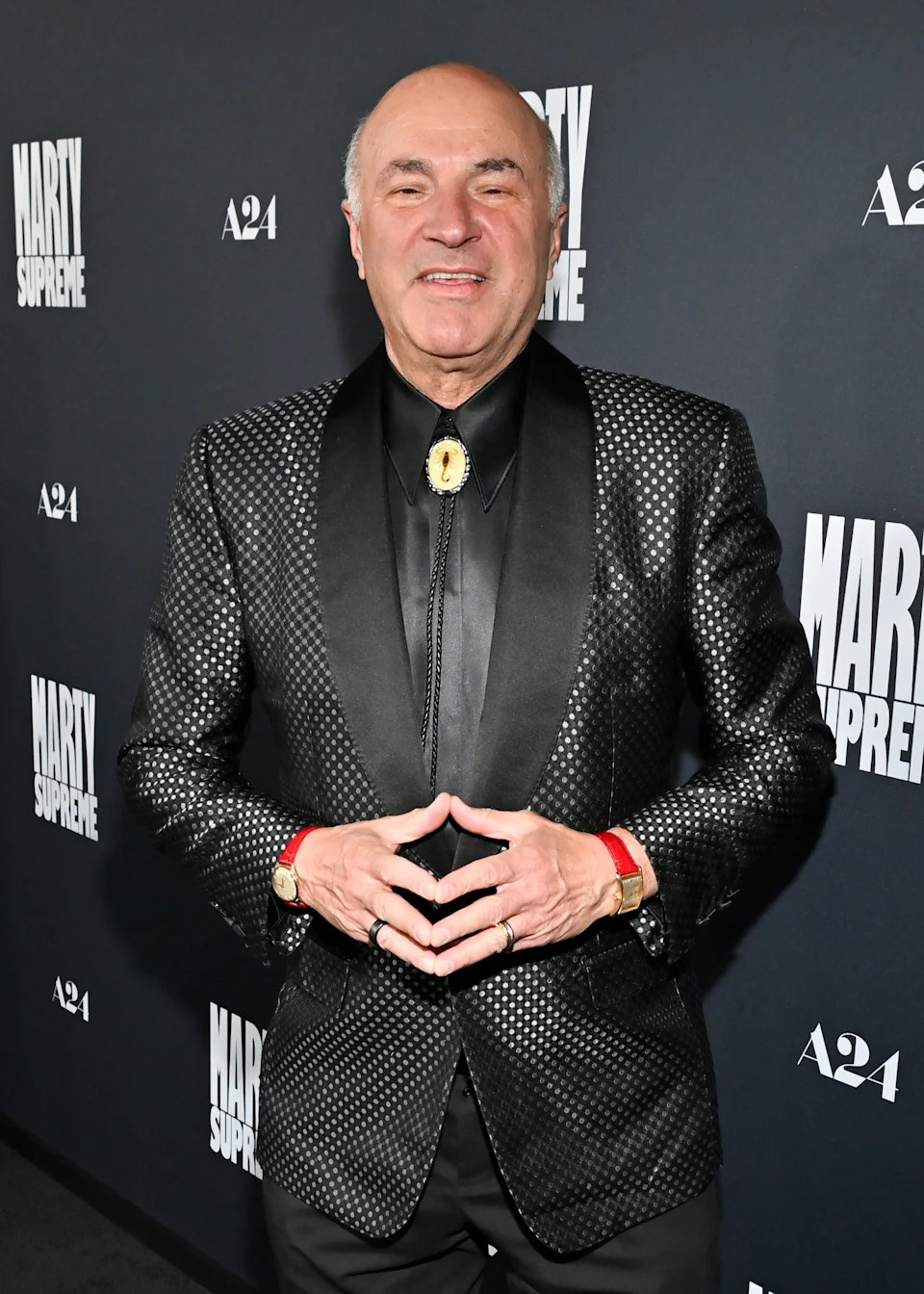 Man in a dotted suit and black shirt, posing on a red carpet at an event