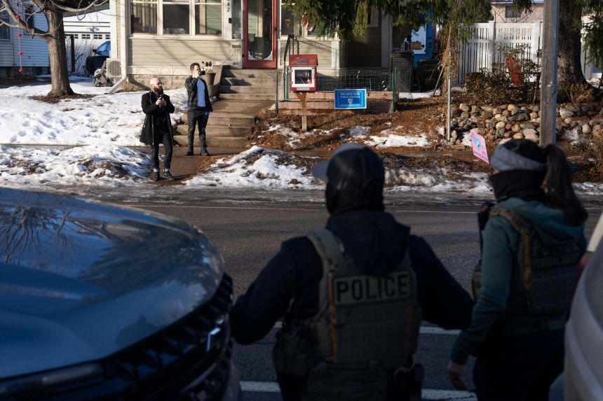 Community members film with their phones from across the street on January 13, 2026, as federal agents conduct an immigration raid days after an ICE agent fatally shot Renee Nicole Good in Minneapolis.