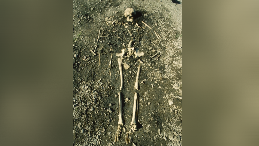 a female skeleton in the ground with two small child skeletons near her shoulders