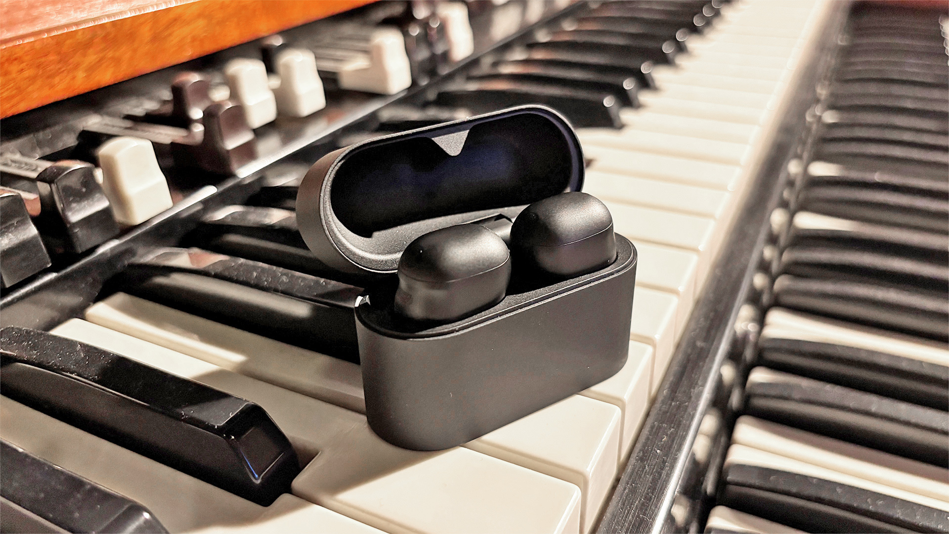 Sony WF-1000XM6 wireless earbuds in open case on electric piano keyboard