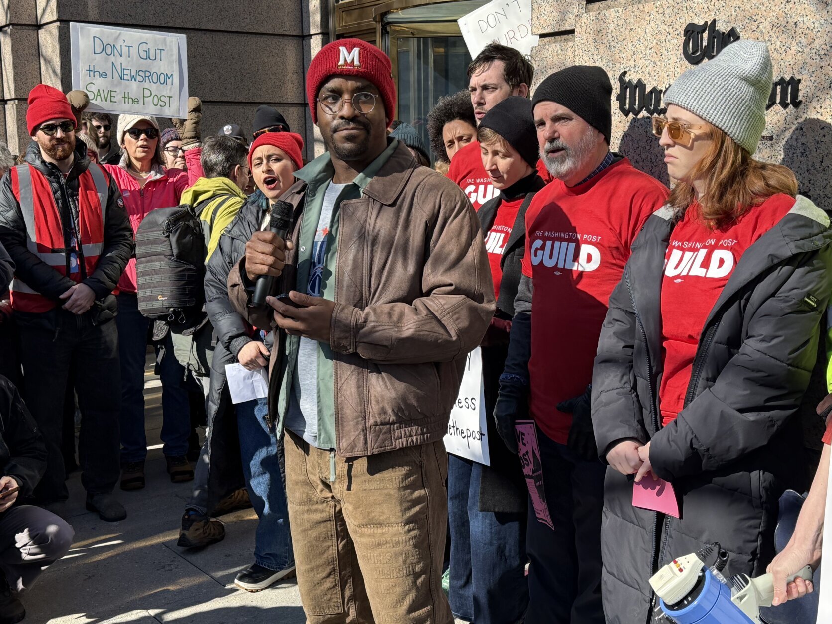 a man speaks into a microphone in front of a group of people