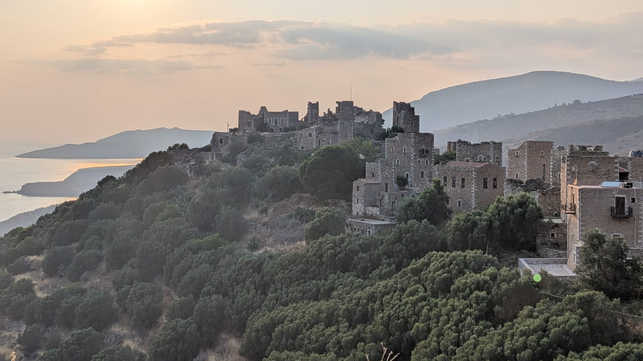 a scene of several fortified houses on a hill in the sunset