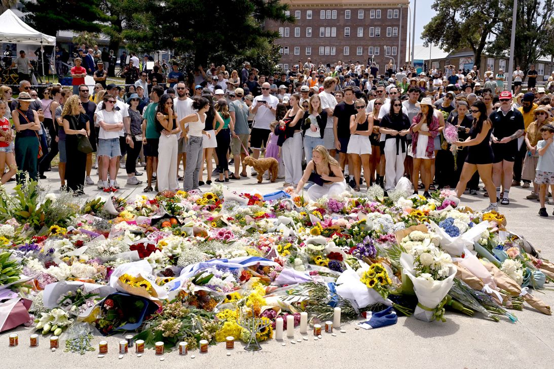 Mourners gather by floral tributes at the Bondi Pavillion in memory of the victims of a shooting at Bondi Beach, in Sydney on December 15, 2025.