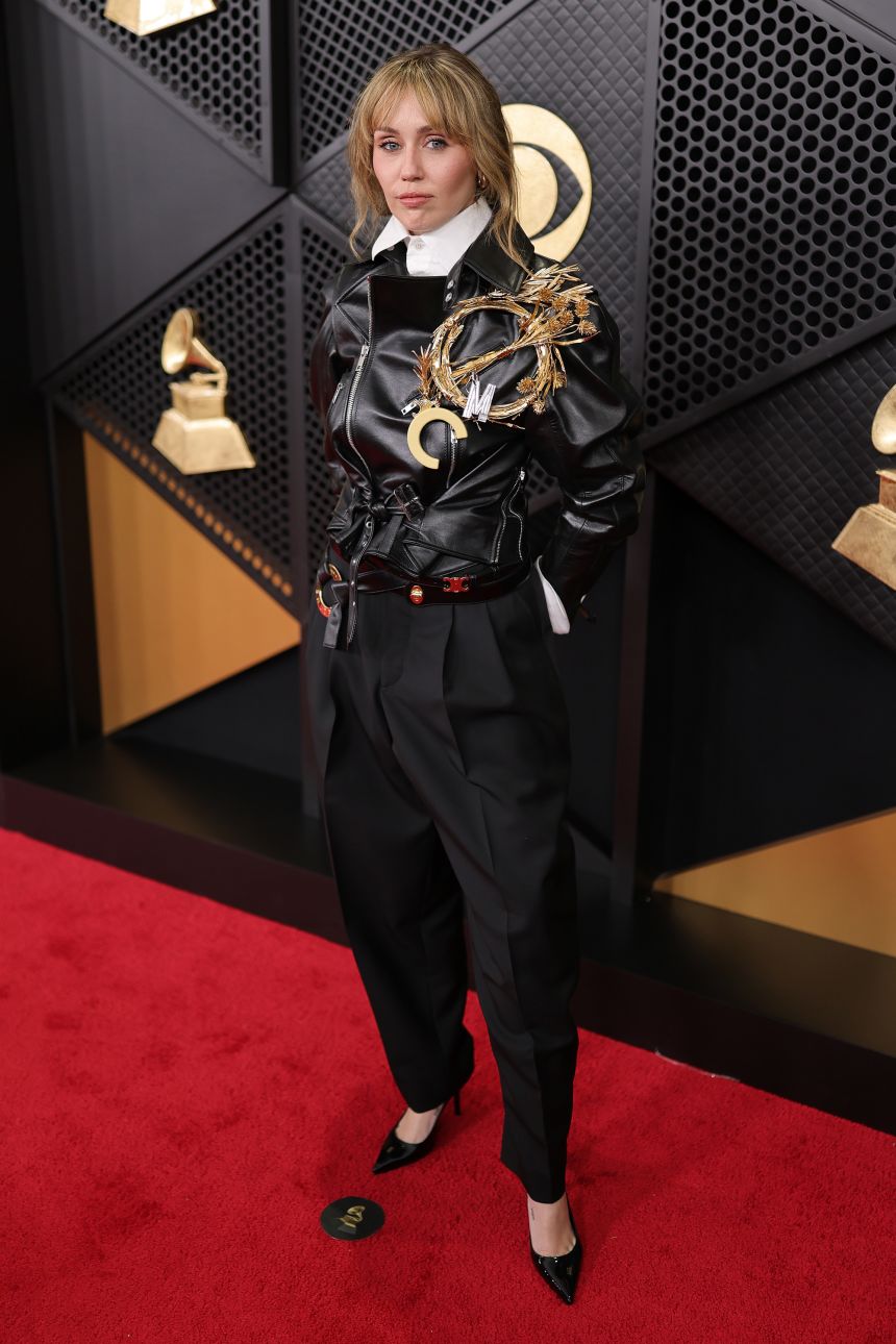 Miley Cyrus, wearing Celine, arrived in tuxedo pants, an oversized white shirt and a chic leather biker jacket adorned with large brooches.