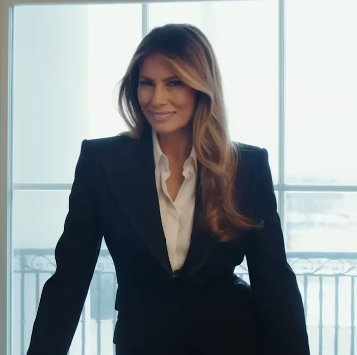 Woman in black blazer and white shirt smiling confidently in front of window, related to theater's hilarious clap back and Amazon pull. Woman in black blazer and white shirt smiling confidently in front of window, related to theater's hilarious clap back and Amazon pull.