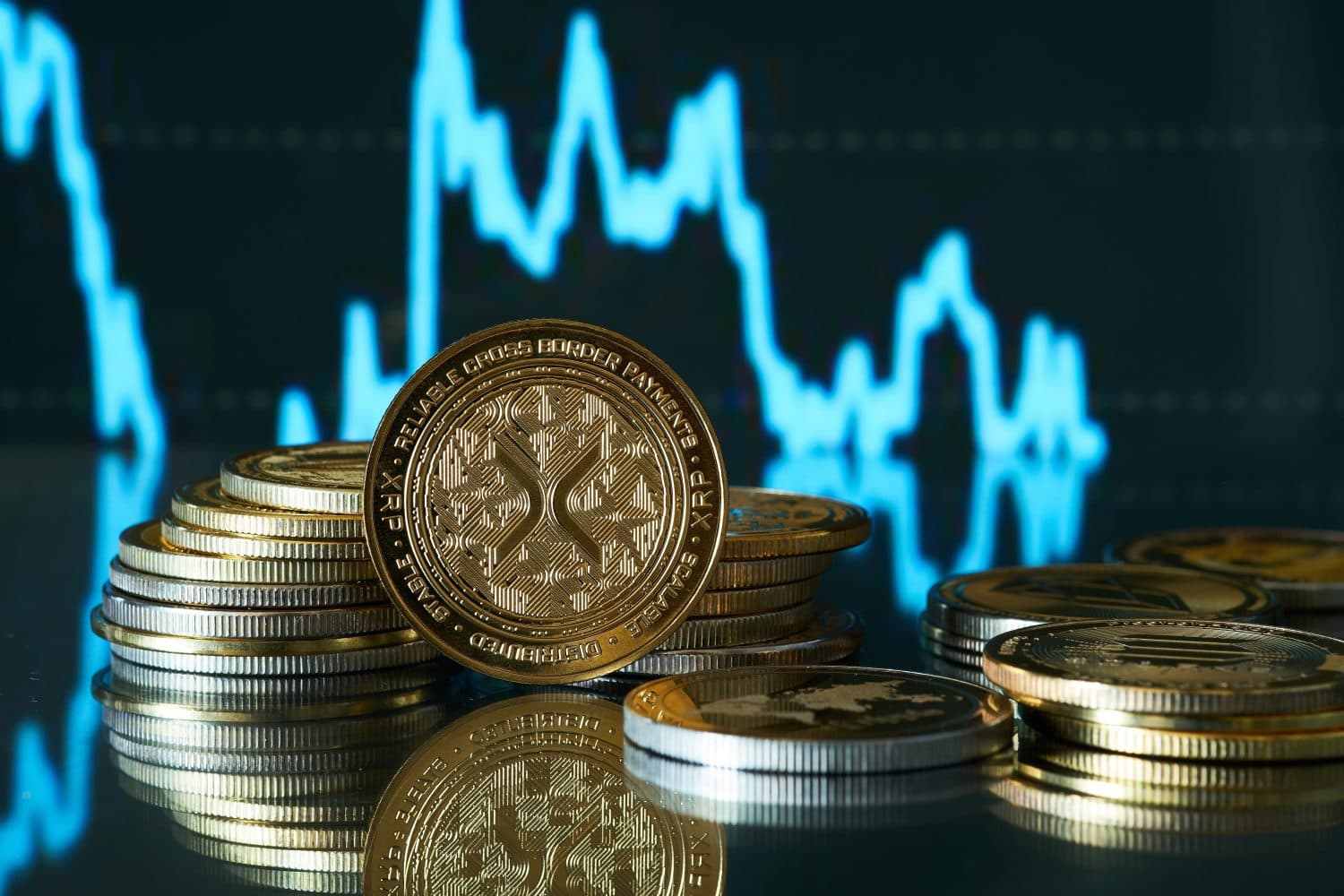 One Xrp coin in front of a stack, with a price chart in the background showing value fluctuations.