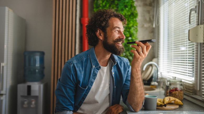 Man talking into smartphone microphone, recording, controlling devices with remote