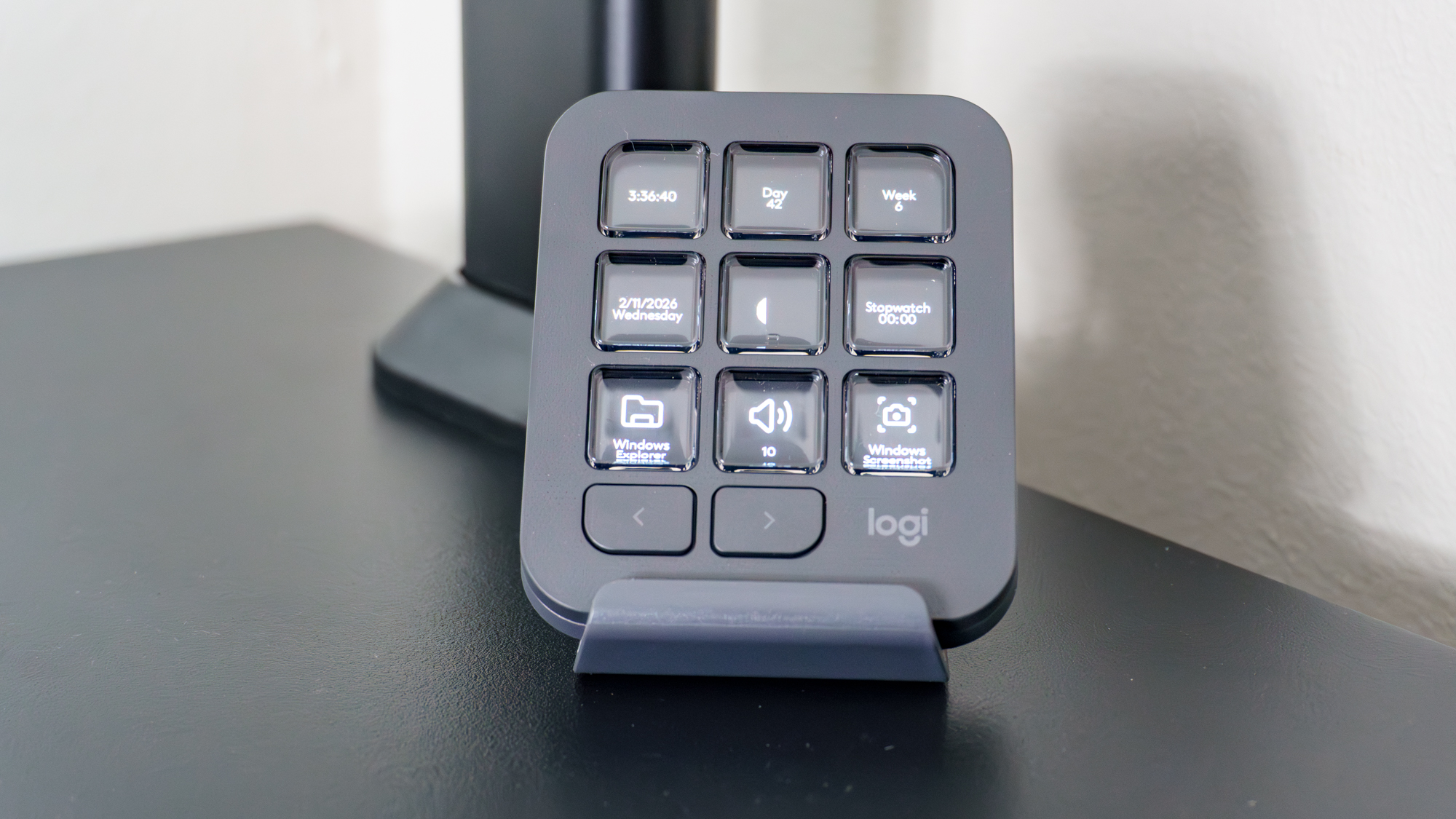 The MX Dialpad from the MX Creative Console on a desk with most of its buttons set to display static info
