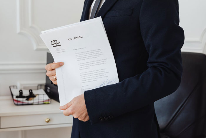 Person in a suit holding a divorce document, symbolizing conflict in parenting and family mediation issues.