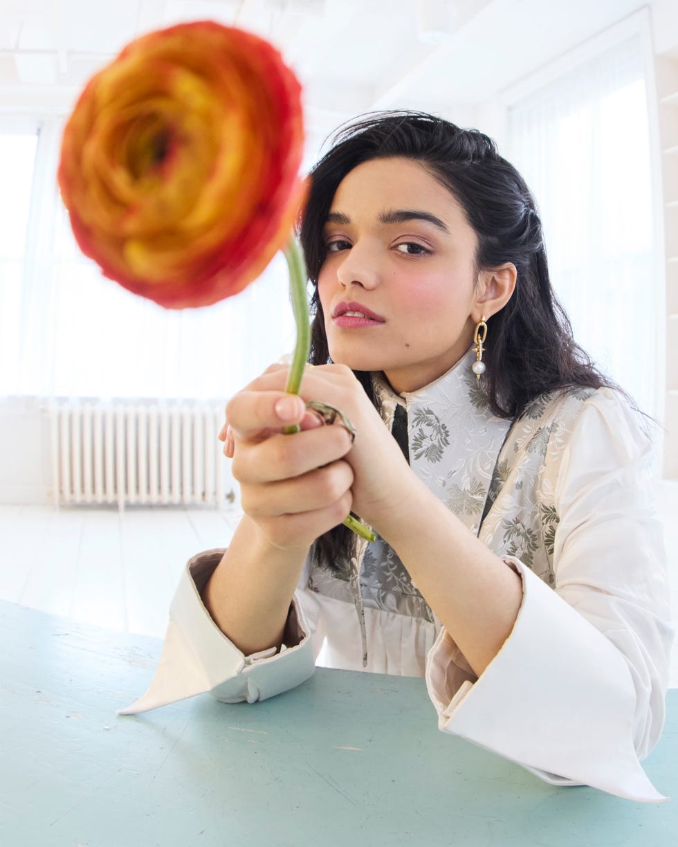 a person holding a colorful flower in a bright airy room