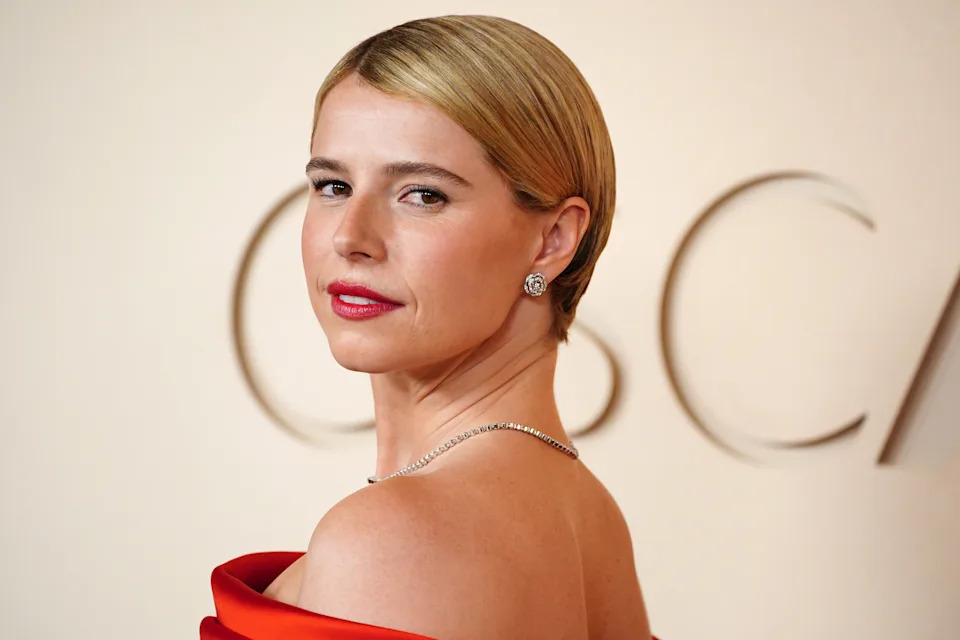 Jessie Buckley with slicked-back hair and a pop of red lipstick.