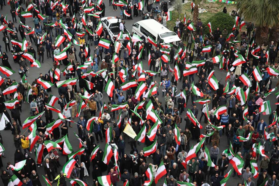A group of demonstrators wave Iranian flags in support of the government and against U.S. and Israeli strikes in Tehran, Iran, Saturday, Feb. 28, 2026.