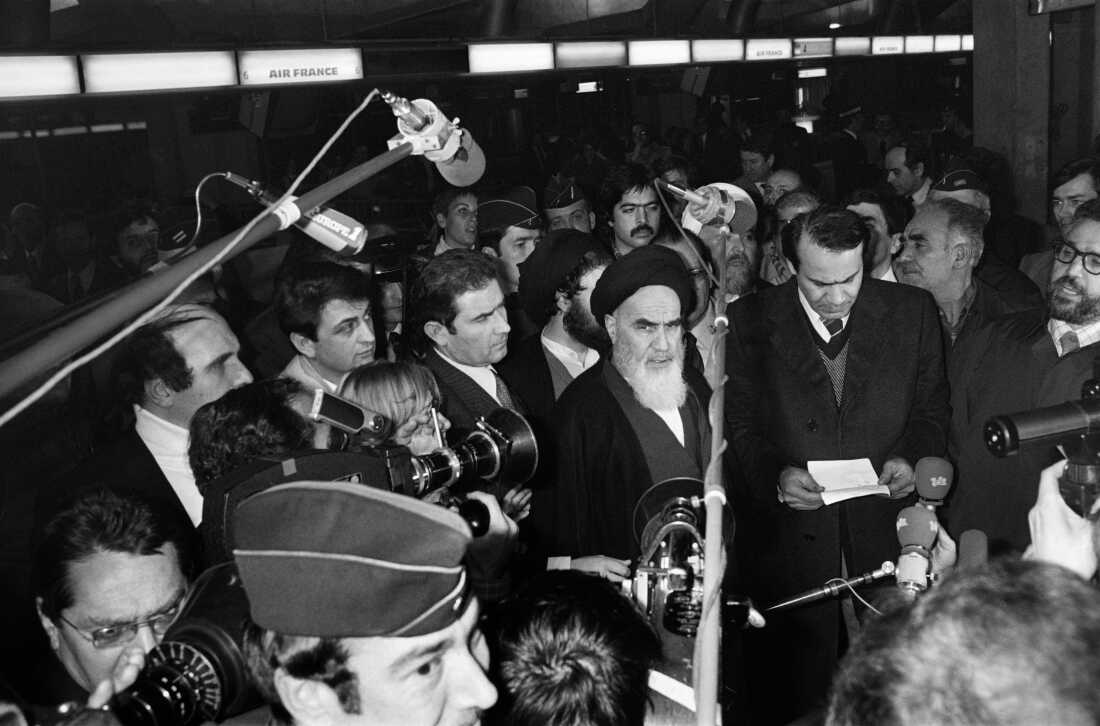 Iranian opposition leader in exile Ayatollah Ruhollah Khomeini gives a speech as journalists surround him at Roissy airport near Paris on Jan. 31, 1979, before boarding a plane bound for Tehran. Khomeini establishes an Islamic republic in Iran.