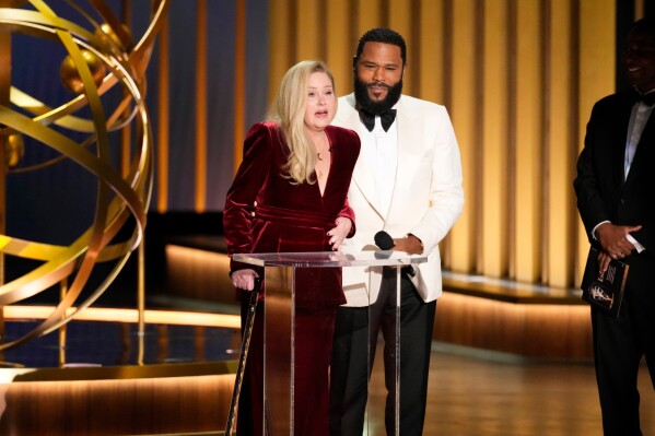 Christina Applegate, left, is assisted by Anthony Anderson as she presents the award for outstanding supporting actress in a comedy series during the 75th Primetime Emmy Awards in Los Angeles on Jan. 15, 2024. (AP Photo/Chris Pizzello, File)