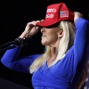 Then-Rep. Marjorie Taylor Greene puts on her red "Make America Great Again" baseball cap while addressing a campaign rally for then-candidate Donald Trump in March 2024 in Rome, Georgia.