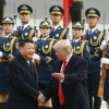 President Trump and Chinese President Xi Jinping shake hands at a welcoming ceremony on November 9, 2017, in Beijing. Two rows of military personnel wearing uniforms and carrying rifles with bayonets stand in the background.