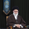 In this 2017 photo, Ayatollah Ali Khamenei, wearing a turban and traditional clothing, sits on a chair. A framed portrait of Ayatollah Ruhollah Khomeini stands on a table on the right side of the frame.