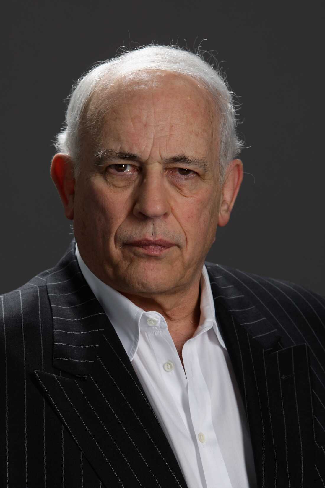 A portrait-style photo of John Brockman. He's photographed from about the torso up. He's wearing a white shirt and a dark sport coat.