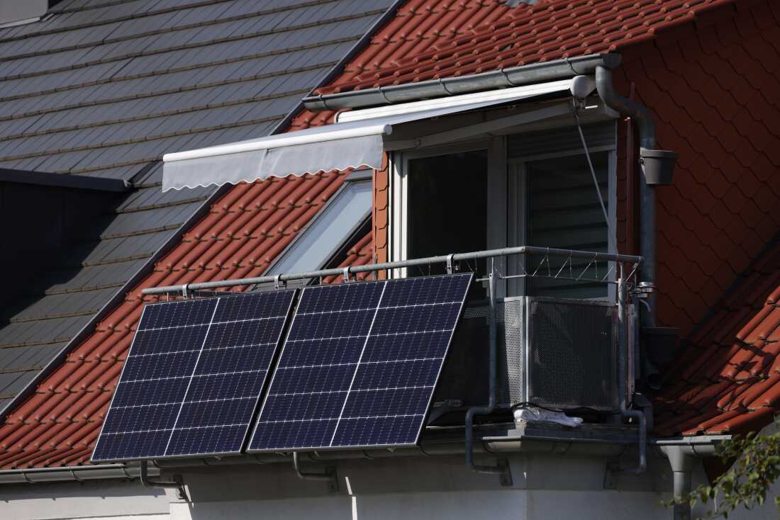 Black rectangular solar energy panels hang outside a residential apartment balcony in Erfurt, Germany.