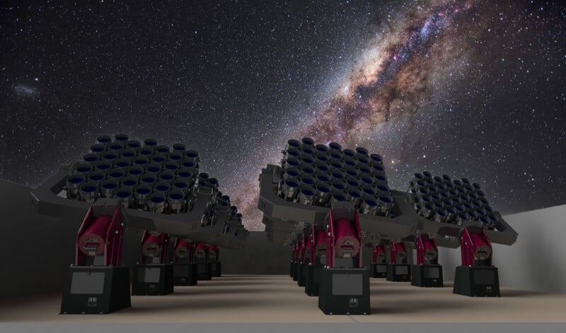 A row of advanced telescopes with multiple lenses points toward a star-filled night sky and the bright arc of the Milky Way, set against a smooth, walled platform.