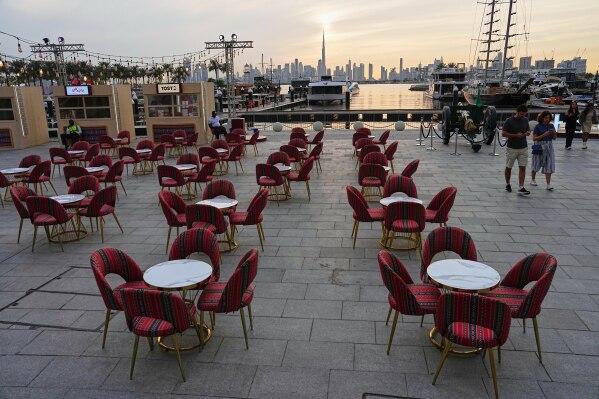 People walk past an outdoor empty restaurant at Dubai Creek Harbour in Dubai, United Arab Emirates, Wednesday, March 11, 2026. (AP Photo/Fatima Shbair)