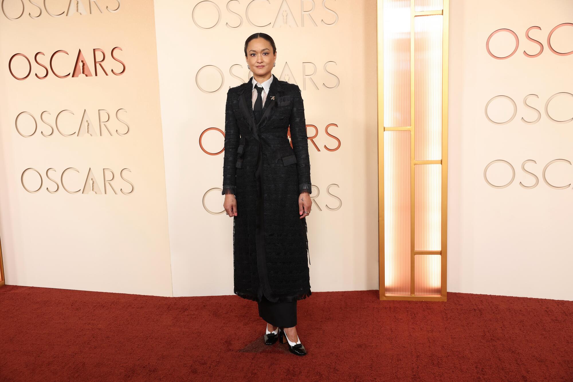 Autumn Durald Arkapaw, wearing a long coat, poses on the red carpet. 