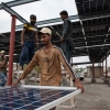 Workers install solar panels on the rooftop of a business.