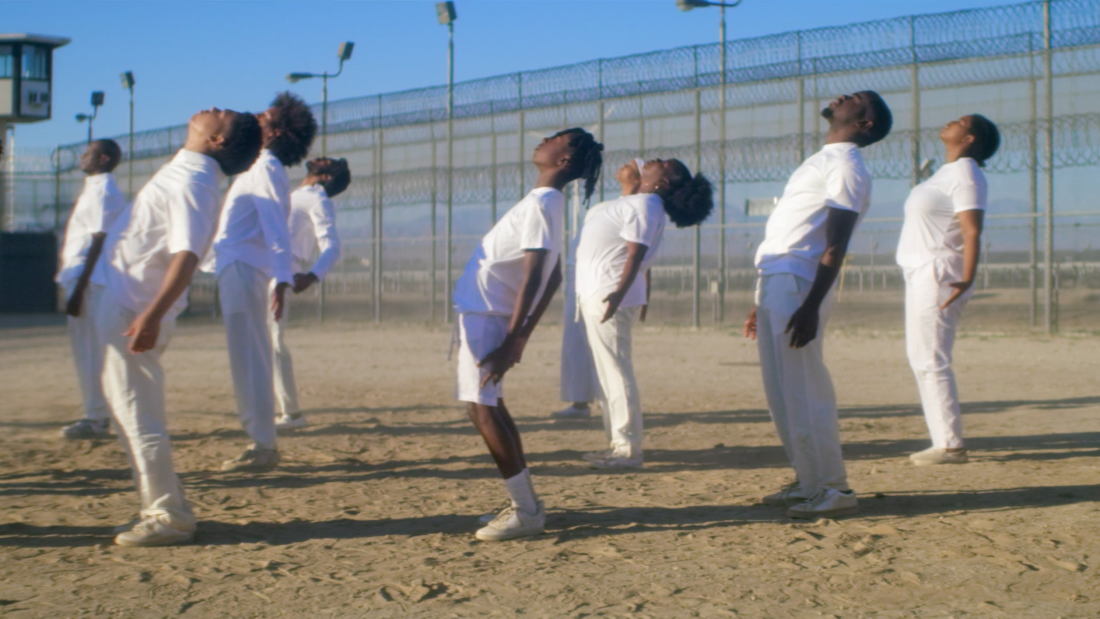 Actors gaze up to the sky during JJ'88's "ROOT" in the hip-hop artist and former inmate's documentary/visual album Songs from the Hole. Before the song starts, protagonist and producer James "JJ'88" Jacobs describes meditating on his and others' redemption while incarcerated and in solitary confinement.