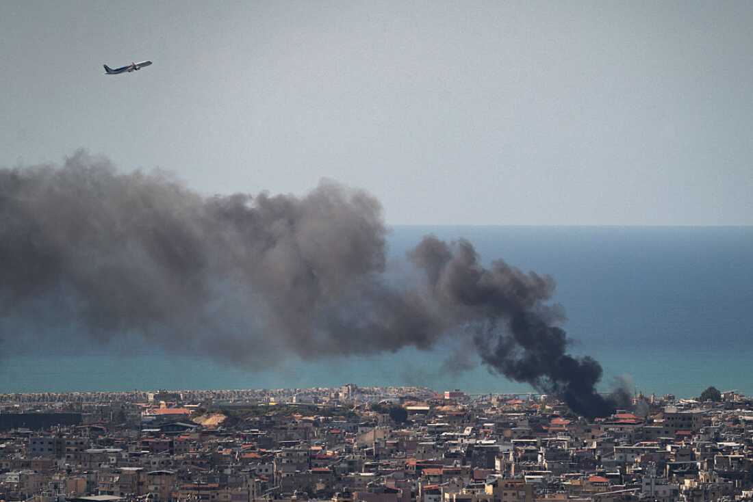 MEA commercial airplane is flying above the smoke after an IDF airstrike on March 17, 2026 in Beirut, Lebanon.