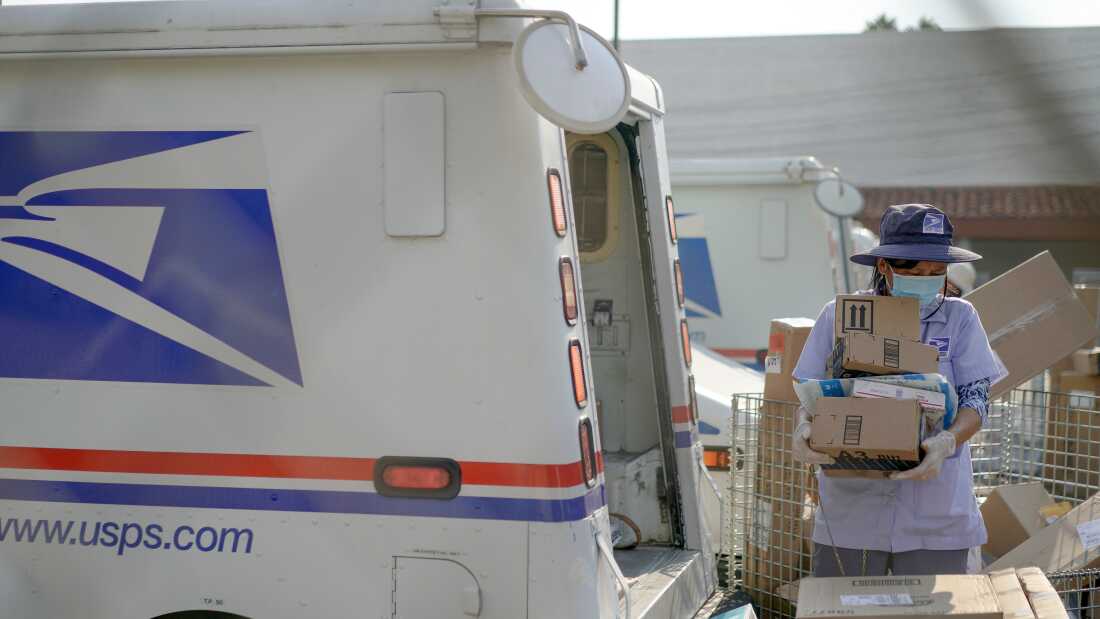 A U.S. Postal Service worker sorts packages behind a mail truck in Los Angeles in 2020.