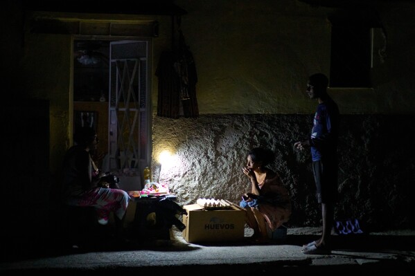 Street vendors chat during a blackout in Havana, Monday, March 16, 2026. (AP Photo/Ramon Espinosa)