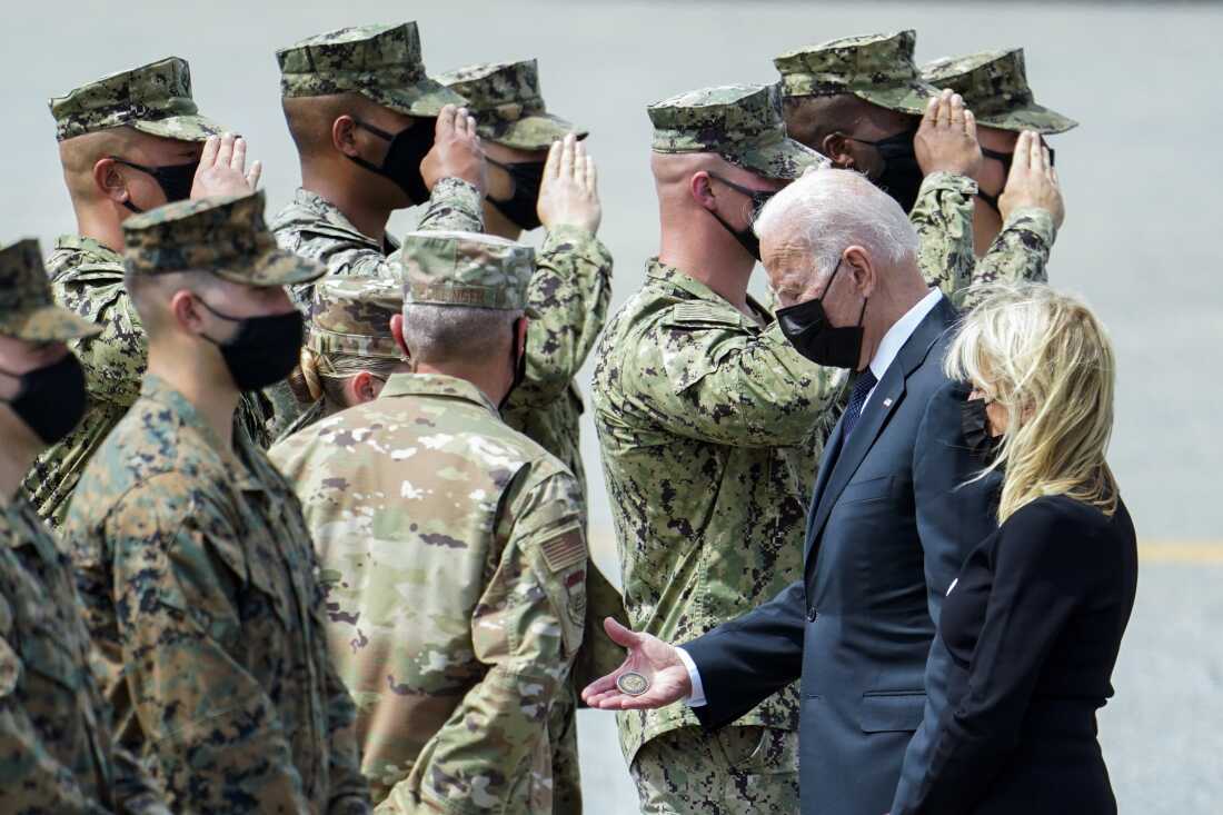 President Joe Biden holds a presidential challenge coin as he speaks with Air Force Mortuary Affairs Operations Air Force Col. Chip Hollinger and others after participating in a casualty return Aug. 29, 2021, at Dover Air Force Base.
