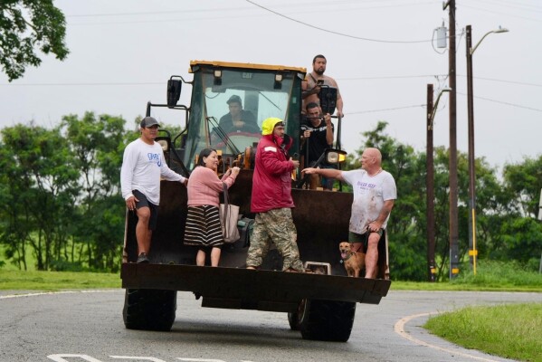 People are evacuated from Haleiwa, Hawaii, on a bulldozer Friday, March 20, 2026. (Craig Fujii/Honolulu Civil Beat via AP)