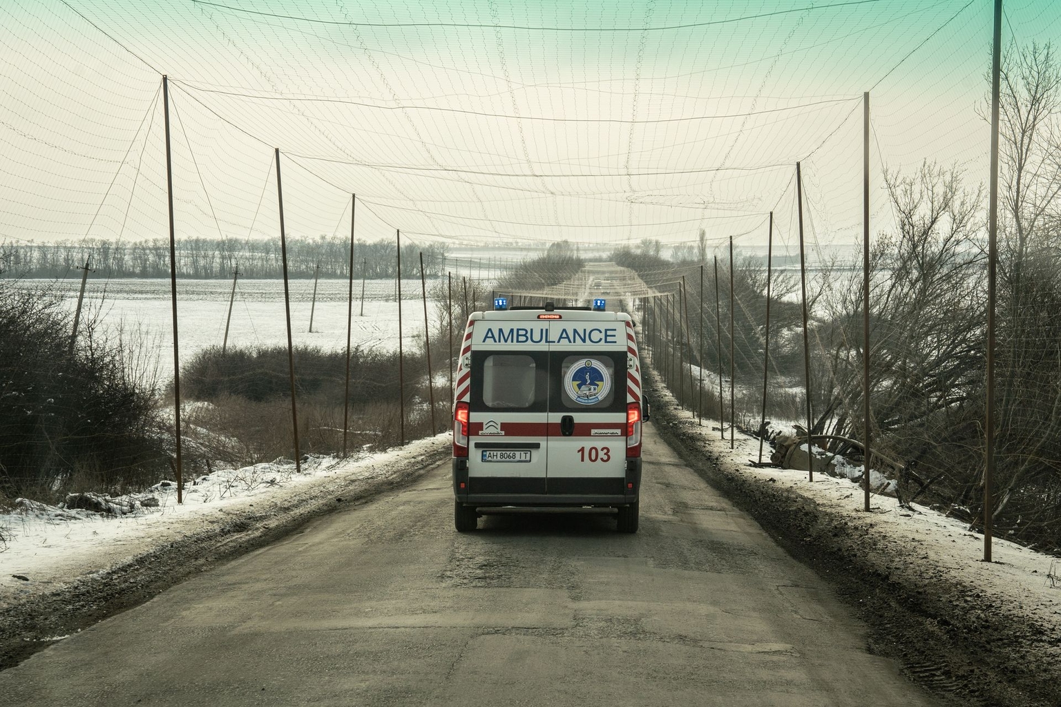 A Ukrainian ambulance drives along a road in Donbas covered by protective anti-drone nets in Donetsk Oblast on Jan. 23, 2026.