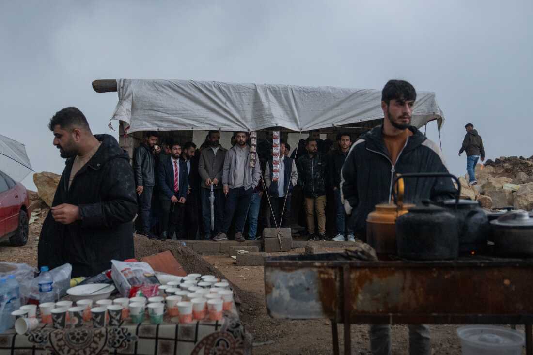 People stand under a tent on a hilltop to avoid the pouring rain while waiting for the Nowruz festivities to begin on friday evening.