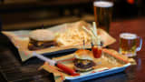 A mini burger, mini fries and mini beer, Clinton Hall's "Teeny Weeny Mini Meal", is pictured next to a regular-sized combo on Dec. 8, 2025 in New York City. Approximately one in eight American adults are currently taking drugs from the class of GLP-1 agonists that are now popular for weight loss, according to a November poll by the non-profit health policy tracker KFF. Some in the restaurant industry are taking note.